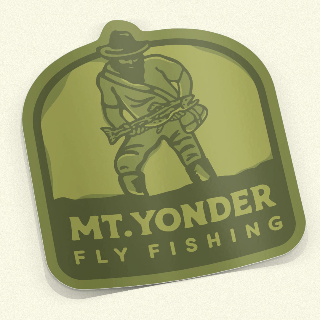 Three-tone Green Sticker with the Mt. Yonder Fly Fishing Logo. A vintage looking mountain man with a big beard standing in water holding a big trout.